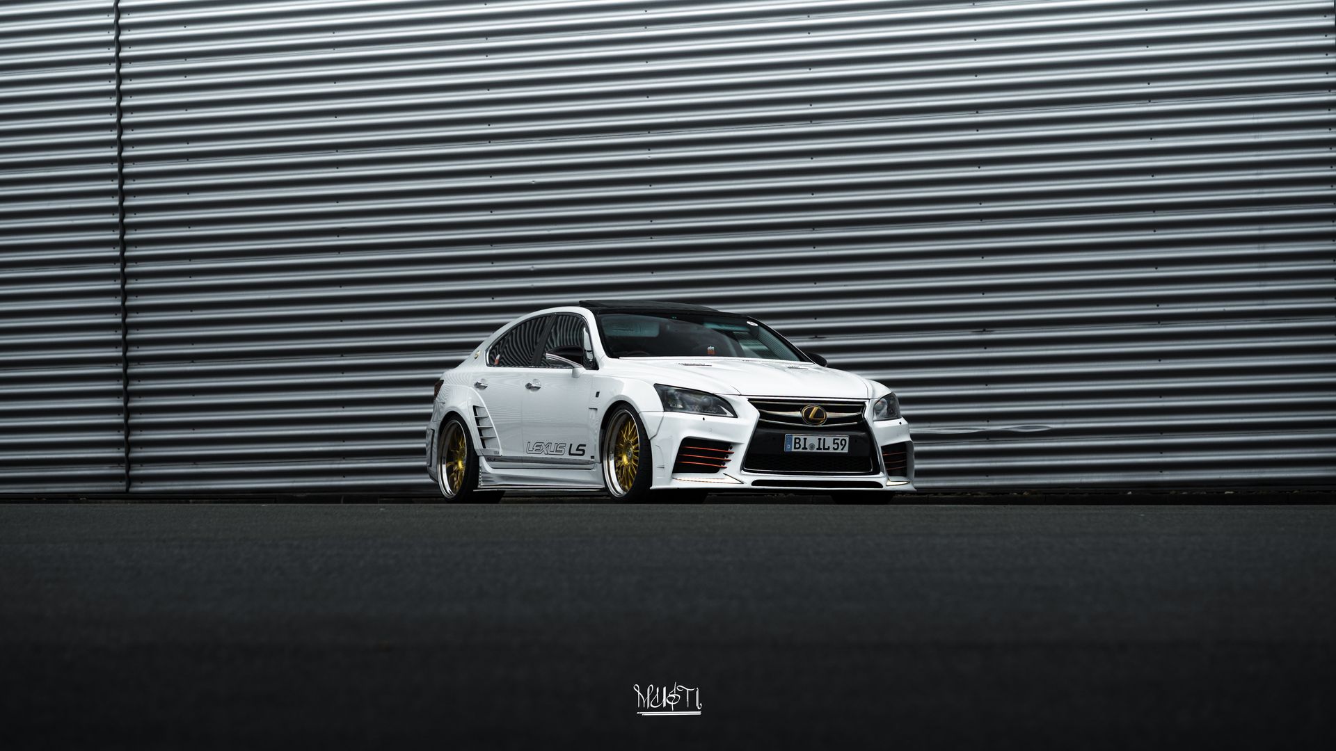 Weißer Lexus LS mit individuellen goldenen Felgen vor einer Industriehalle